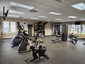 A gym with a variety of exercise equipment including treadmills, stationary bikes, and weight machines.